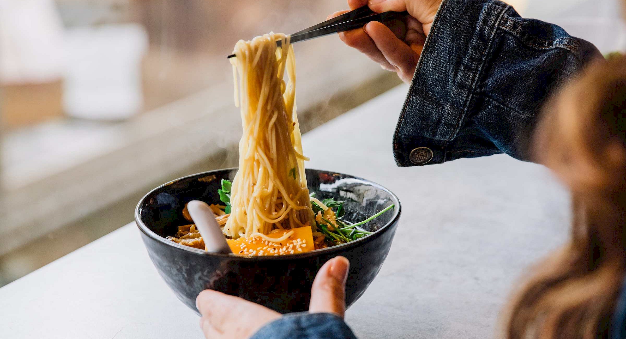A close up of steaming noodles in a ramen dish