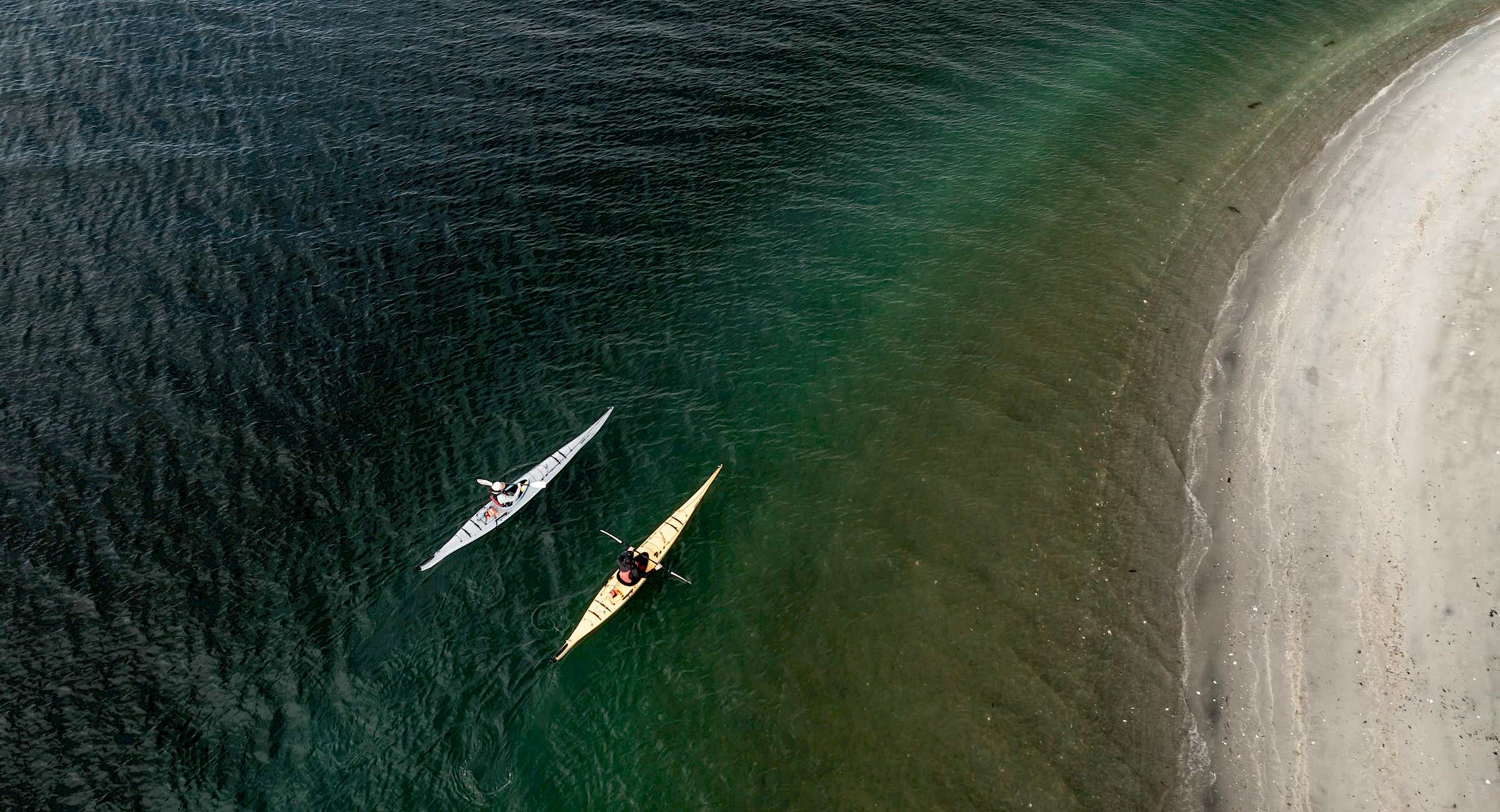 An aerial shot of two kayaks on the ocean